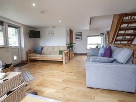 A living room with a sofa, futon, and television at The Hayloft in Bodelwyddan