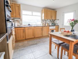 A kitchen with wooden cabinets and a table with fruit at The Hayloft in Bodelwyddan