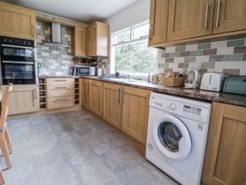 A kitchen with cabinets, a washing machine, and appliances at The Hayloft in Bodelwyddan