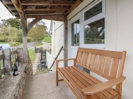An outdoor seating area with a wooden bench and champagne at The Hayloft in Bodelwyddan