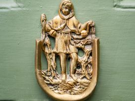 A brass door knocker depicting a figure with a fishing theme