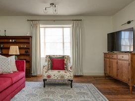 A living room with a red sofa and a decorative armchair at Apartment 2, 86 Dyer Street Cirencester