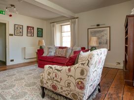 A living room with a red sofa and a floral armchair at Apartment 2, 86 Dyer Street Cirencester