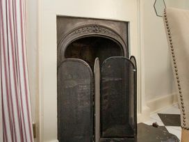 A fireplace with a guard in a living room at Apartment 2, 86 Dyer Street Cirencester