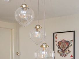 A hanging light fixture with three bulbs and wall art at Apartment 2, 86 Dyer Street Cirencester