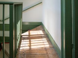 A staircase with wooden floor and green railing at Apartment 2, 86 Dyer Street Cirencester