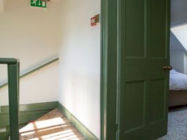 A staircase with a green door and emergency exit sign at Apartment 2, 86 Dyer Street, Cirencester