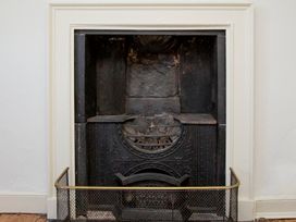 A fireplace with a metal grate at Apartment 2, 86 Dyer Street Cirencester