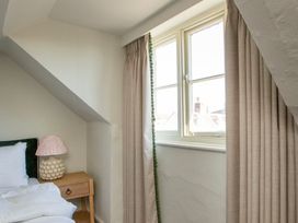 A bedroom with a bed, lamp, and window at Apartment 2, 86 Dyer Street Cirencester