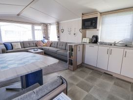 A living room with a sofa, table and kitchen area at V9 Ty Mawr Holiday Park