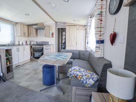 A living room with a kitchen area and sofa at V9 Ty Mawr Holiday Park