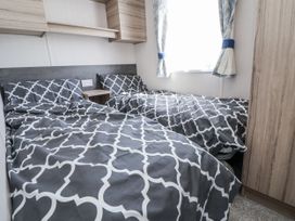 A bedroom with twin beds and wooden cabinets at V9 Ty Mawr Holiday Park