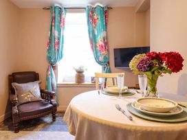 A dining room with a table set for two and a television at Bwthynbach in Porthmadog
