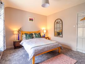 A bedroom with a bed, lamp, and mirror at Bwthynbach in Porthmadog