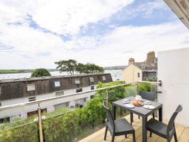 A balcony with a table and chairs overlooking water at 9 Slipway Cottages in Rock