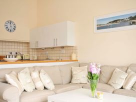 A living room with a sofa and kitchen area at 9 Slipway Cottages in Rock