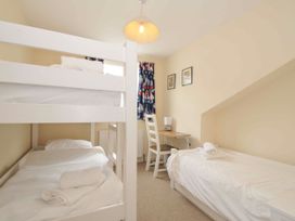 A bedroom with bunk bed and single bed at 9 Slipway Cottages, Rock