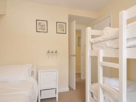 A bedroom with a bunk bed and single bed at 9 Slipway Cottages Rock