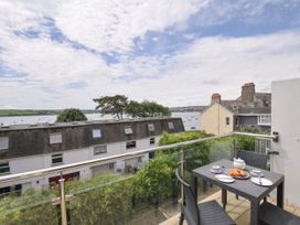 A balcony with a table and chairs overlooking the water at 9 Slipway Cottages in Rock