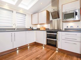 A kitchen with white cabinets and appliances at The Maples 44 in St. Austell