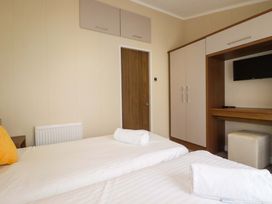 A bedroom with two beds and a television cabinet at The Maples 44 St. Austell