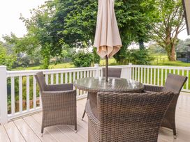 A patio with a table and chairs under an umbrella at The Maples 44 St. Austell