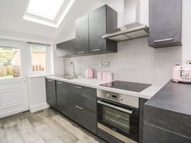 A kitchen with cabinets, sink, stove, and toaster at Billy's Cottage in Maryport