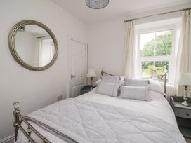 A bedroom with a bed and a mirror at Billy's Cottage in Maryport