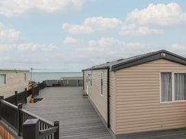 A mobile home with a deck overlooking the sea at Hafan Y Mor in Aberporth
