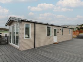 A mobile home with a deck and windows at Hafan Y Mor in Aberporth