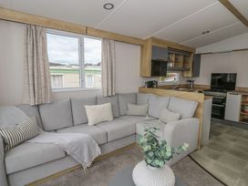 A living room with a sofa and kitchen area at Hafan Y Mor in Aberporth