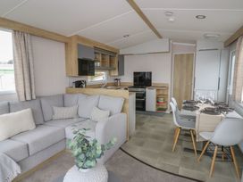 A living room with a sofa and dining area at Hafan Y Mor in Aberporth