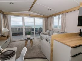 A living room with a sofa, table, and lamp at Hafan Y Mor in Aberporth
