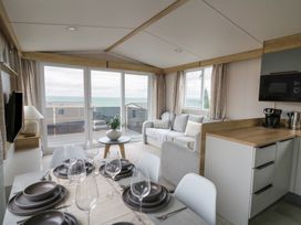 A living room with a dining area and sea view at Hafan Y Mor Aberporth