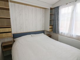 A bedroom with a bed and shelves at Hafan Y Mor in Aberporth
