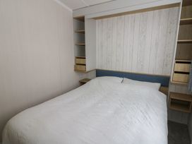 A bedroom with a bed and shelving at Hafan Y Mor in Aberporth