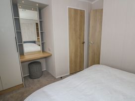 A bedroom with a bed and a mirror at Hafan Y Mor in Aberporth