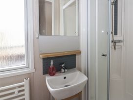 A bathroom with a sink and mirror at Hafan Y Mor in Aberporth