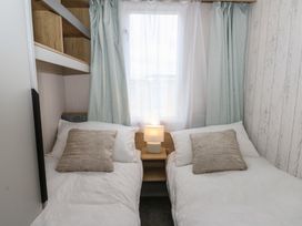 A bedroom with two beds and a lamp at Hafan Y Mor in Aberporth