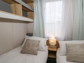 A bedroom with two beds and a lamp at Hafan Y Mor in Aberporth