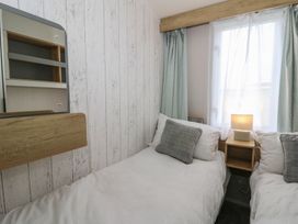 A bedroom with twin beds and a lamp at Hafan Y Mor in Aberporth