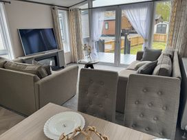 A living room with a sofa, television, and table at Lime Tree Lodge