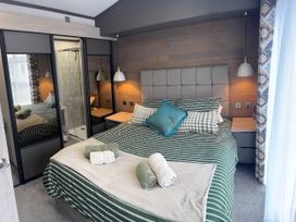 A bedroom with a bed and wardrobe at Lime Tree Lodge St Fillans