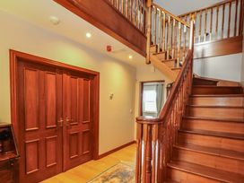 A hallway with a staircase and wooden doors at Ash House in Ballyvaughan
