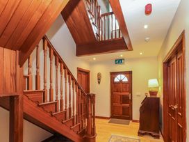 A hallway with a staircase and wooden door at Ash House in Ballyvaughan