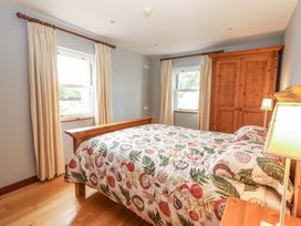 A bedroom with a bed, a wardrobe, and a lamp at Ash House in Ballyvaughan
