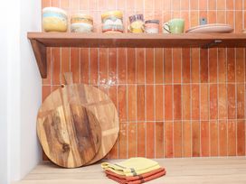 A kitchen with cups on a shelf and a cutting board at Tigley Meadow Coach House in Totnes