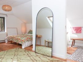A bedroom with a bed, mirror, and table at Tigley Meadow Coach House in Totnes
