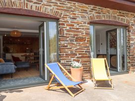 An outdoor area with deck chairs and a view of an indoor living space at Tigley Meadow Coach House in Totnes