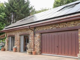 An exterior view of a building with a stone wall and solar panels at Tigley Meadow Coach House in Totnes